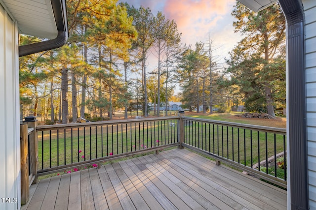 deck at dusk featuring a lawn