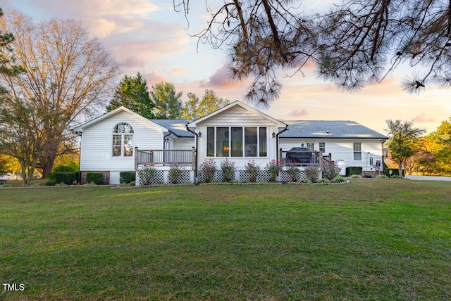 view of front facade with a yard, a wooden deck, and a sunroom