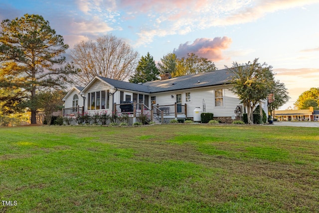 back house at dusk with a sunroom and a yard