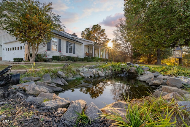 exterior space featuring a garage and a garden pond