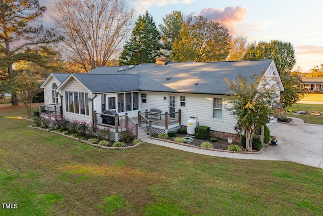 view of front of property featuring a sunroom, a yard, and a deck