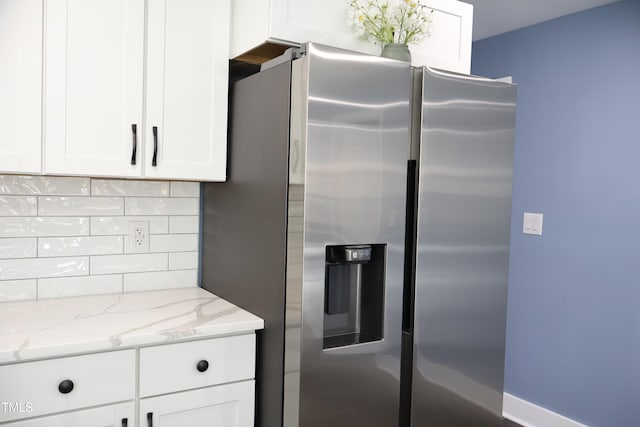 kitchen with decorative backsplash, light stone counters, white cabinetry, and stainless steel refrigerator with ice dispenser