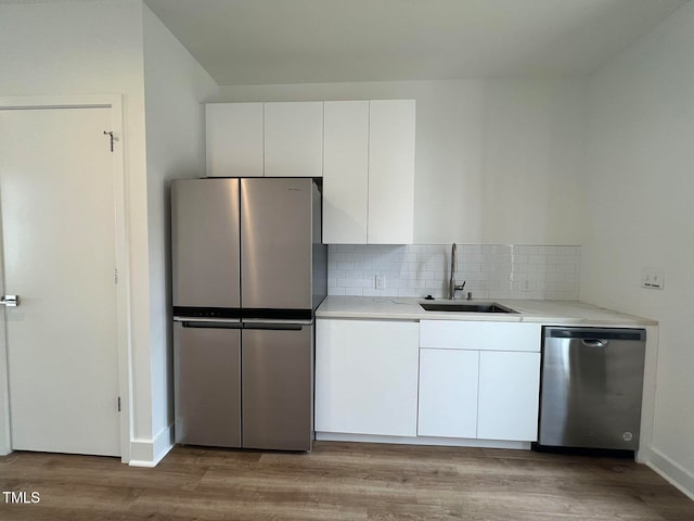 kitchen with sink, white cabinets, light hardwood / wood-style floors, and appliances with stainless steel finishes