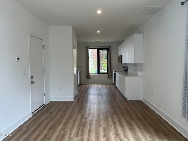 kitchen featuring tasteful backsplash, white cabinetry, hardwood / wood-style floors, and stainless steel appliances