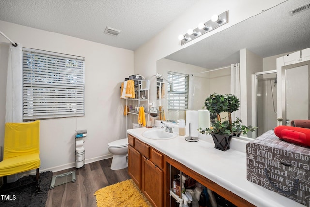 bathroom with an enclosed shower, vanity, a textured ceiling, wood-type flooring, and toilet