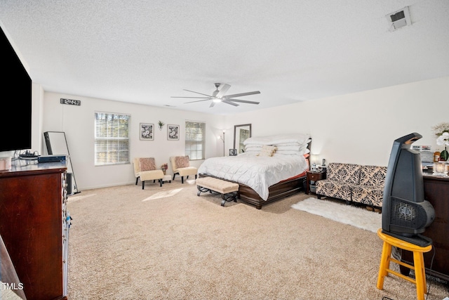 carpeted bedroom with ceiling fan and a textured ceiling