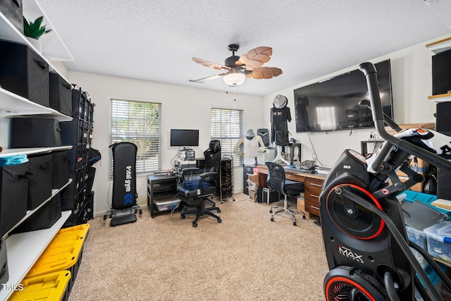 office area with a textured ceiling, ceiling fan, and light carpet