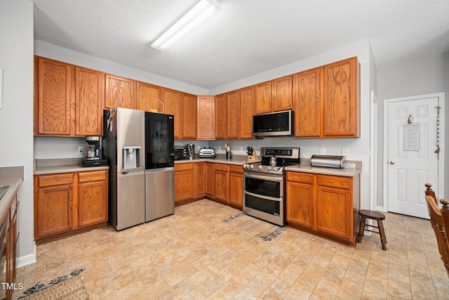 104 Full Moon Ct, Garner, NC 27529 - kitchen with appliances with stainless steel finishes, light countertops, brown cabinets, and a textured ceiling