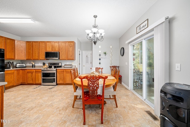 kitchen with hanging light fixtures, light hardwood / wood-style flooring, a textured ceiling, a notable chandelier, and stainless steel appliances