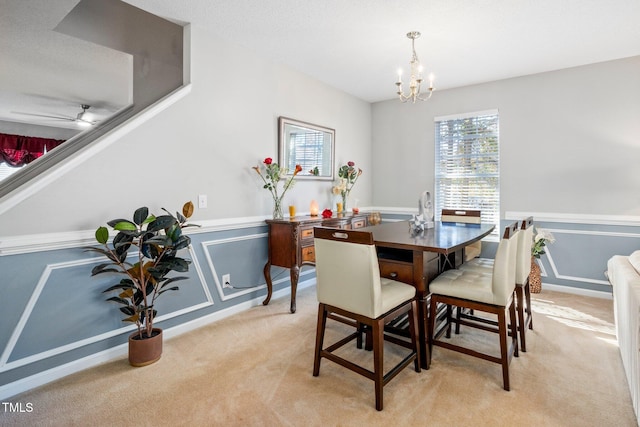 carpeted dining space with ceiling fan with notable chandelier