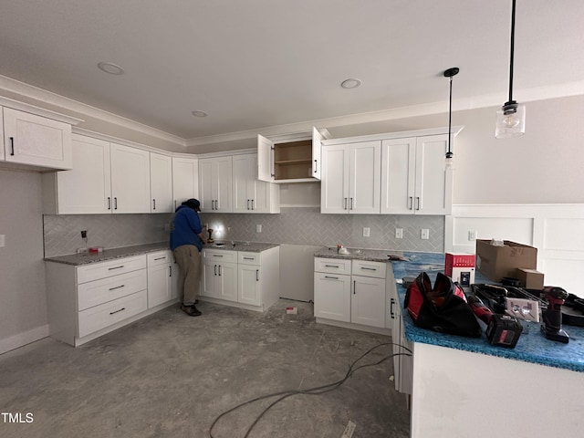 kitchen with tasteful backsplash, white cabinetry, and pendant lighting