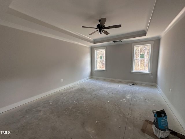 empty room featuring a ceiling fan, a tray ceiling, visible vents, and baseboards