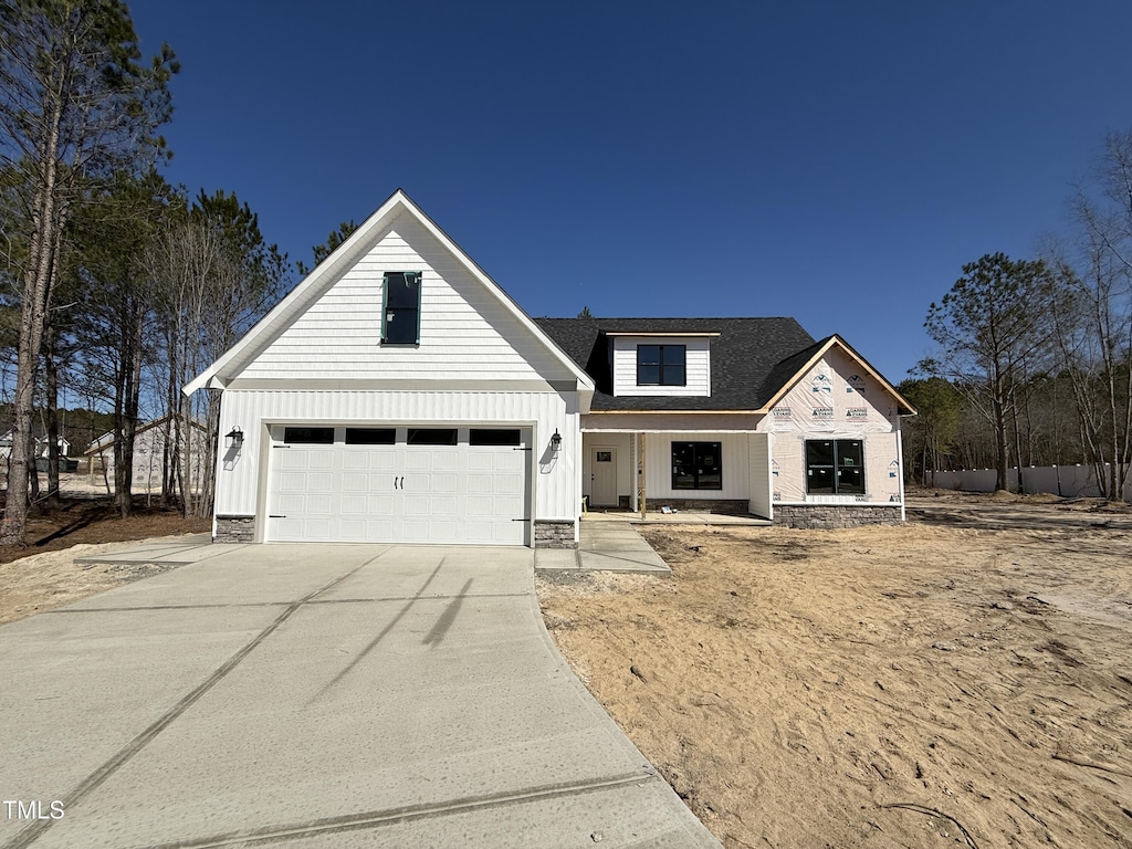 view of front of property with driveway, board and batten siding, and roof with shingles