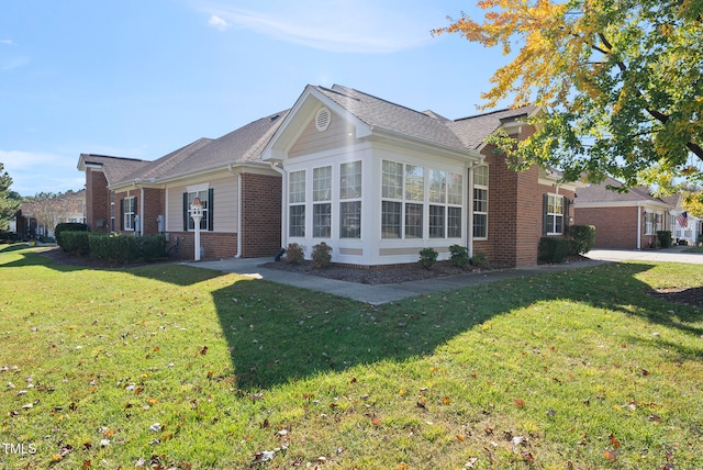 view of property exterior featuring a sunroom and a lawn