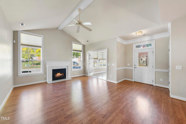 unfurnished living room with vaulted ceiling with beams, a high end fireplace, a healthy amount of sunlight, and hardwood / wood-style flooring