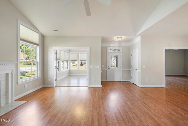 unfurnished living room with light hardwood / wood-style floors, vaulted ceiling, ceiling fan, and a premium fireplace