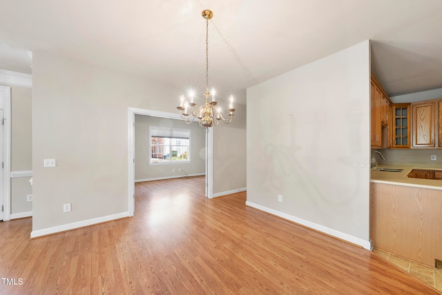 unfurnished dining area with sink, light hardwood / wood-style floors, and an inviting chandelier