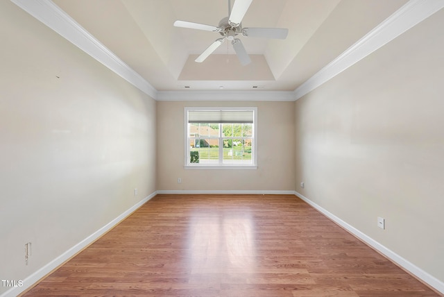 unfurnished room with a tray ceiling, crown molding, and light hardwood / wood-style floors