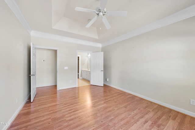 unfurnished bedroom with a tray ceiling, ceiling fan, crown molding, and light hardwood / wood-style floors