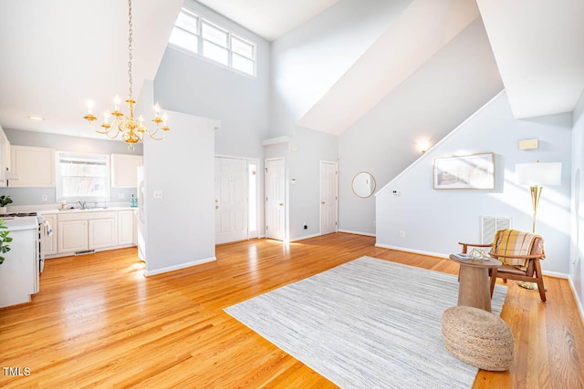 sitting room featuring sink, an inviting chandelier, a high ceiling, and light wood-type flooring