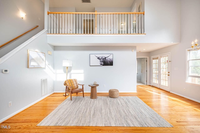 sitting room with a towering ceiling and wood-type flooring