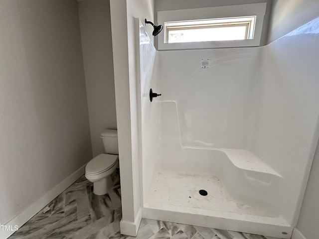 bathroom with toilet, a stall shower, baseboards, and marble finish floor