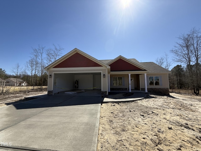 view of front of property featuring board and batten siding, covered porch, concrete driveway, roof with shingles, and a garage