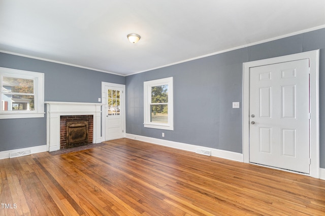 unfurnished living room with crown molding, hardwood / wood-style floors, and a brick fireplace