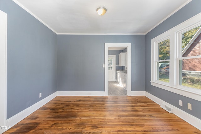 spare room featuring hardwood / wood-style floors, a healthy amount of sunlight, and ornamental molding