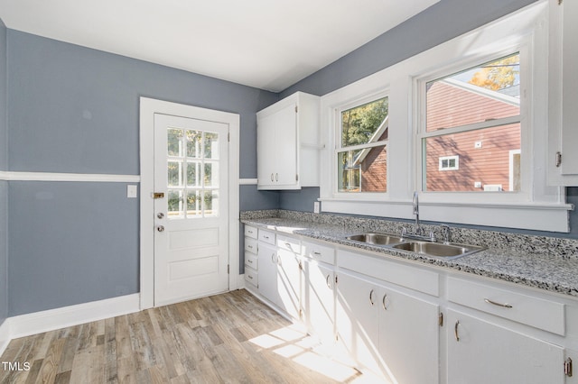 kitchen featuring white cabinetry, light wood-type flooring, sink, and a wealth of natural light