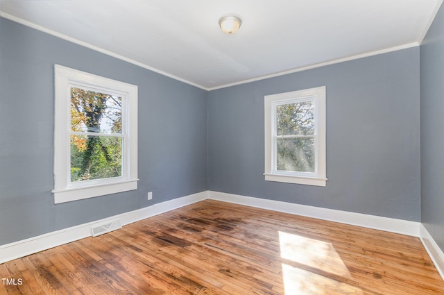 unfurnished room with a healthy amount of sunlight, wood-type flooring, and ornamental molding