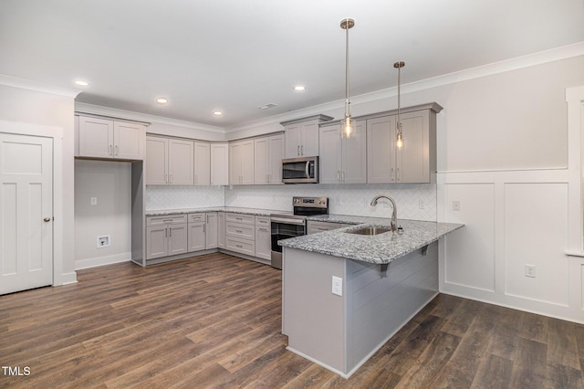 kitchen featuring sink, light stone counters, kitchen peninsula, pendant lighting, and stainless steel appliances