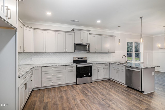 kitchen with decorative light fixtures, light stone countertops, kitchen peninsula, and appliances with stainless steel finishes