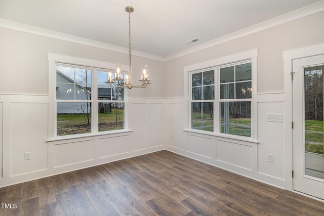 unfurnished dining area with ornamental molding, dark wood-type flooring, a chandelier, and a healthy amount of sunlight