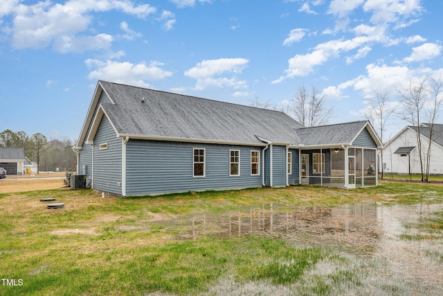 rear view of house featuring central AC unit, a sunroom, and a lawn