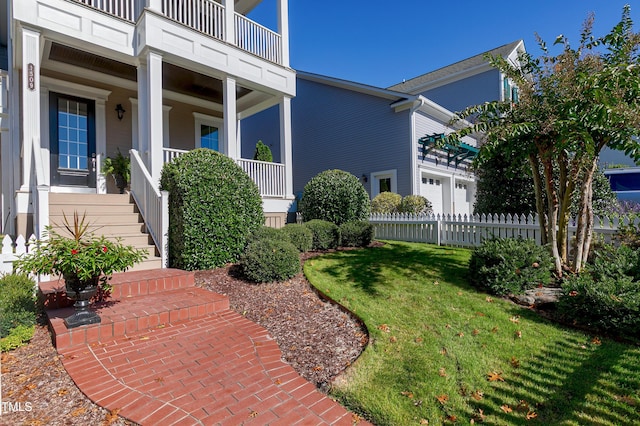 view of exterior entry with a lawn and a balcony