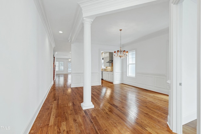 unfurnished dining area featuring hardwood / wood-style flooring, a wealth of natural light, and decorative columns