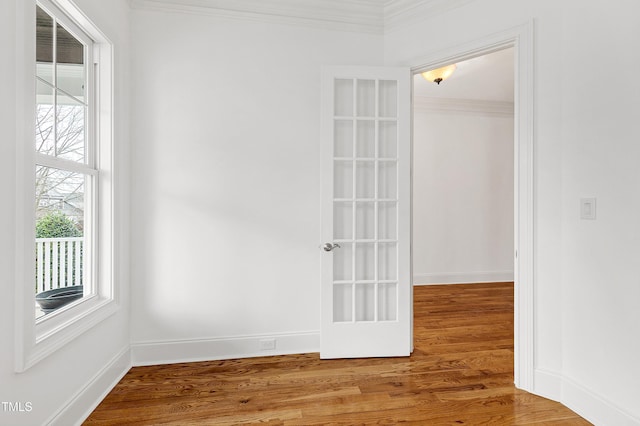 empty room with hardwood / wood-style floors and crown molding