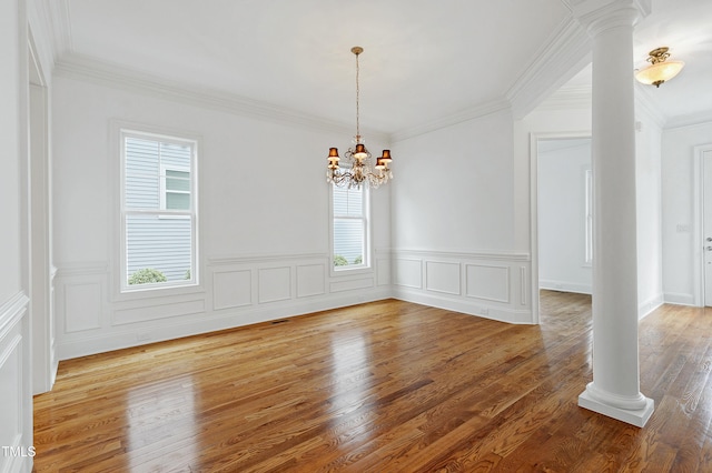 unfurnished dining area featuring decorative columns, hardwood / wood-style floors, and a notable chandelier