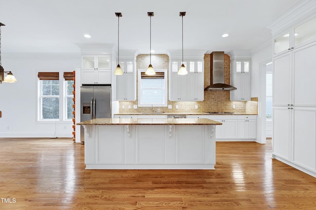 kitchen featuring a kitchen island, sink, wall chimney range hood, and white cabinets