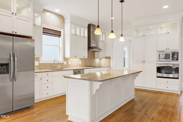 kitchen with white cabinetry, stainless steel appliances, light stone countertops, a kitchen island, and wall chimney exhaust hood