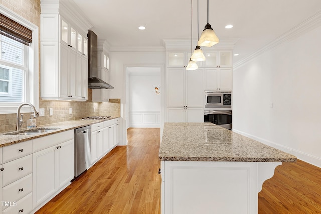 kitchen featuring a kitchen island, appliances with stainless steel finishes, white cabinetry, sink, and wall chimney exhaust hood