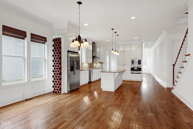 kitchen with white cabinetry, appliances with stainless steel finishes, decorative light fixtures, and a kitchen island