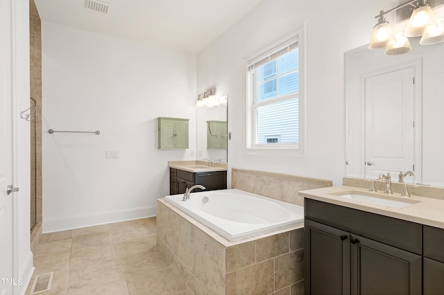 bathroom featuring tile patterned flooring, vanity, and tiled bath