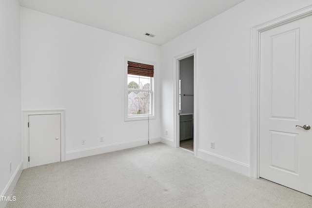 unfurnished bedroom featuring ensuite bath and light carpet