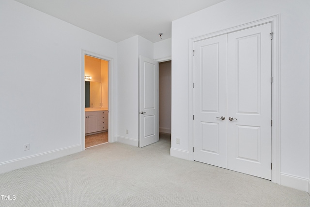 unfurnished bedroom with light carpet, ensuite bath, and a closet