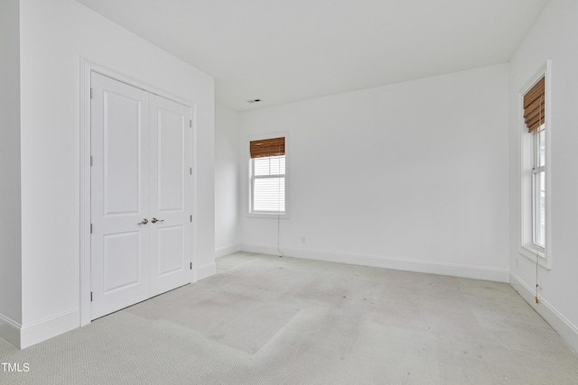 unfurnished bedroom featuring light colored carpet and a closet