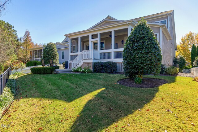 view of front of property with ceiling fan, a front yard, a sunroom, and a porch