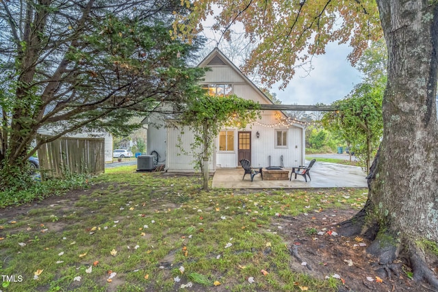 rear view of property featuring cooling unit, an outdoor fire pit, a patio area, and a lawn