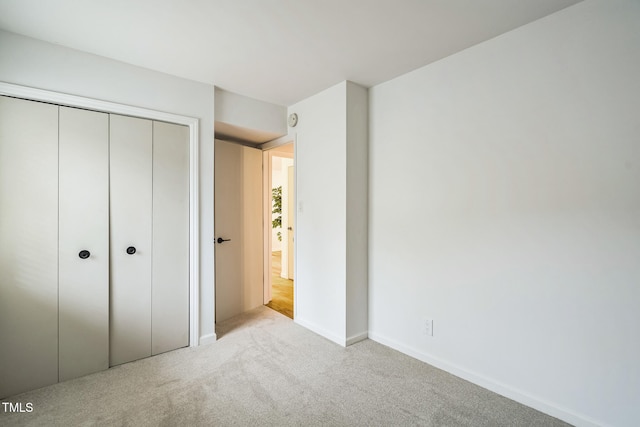 unfurnished bedroom featuring light colored carpet and a closet